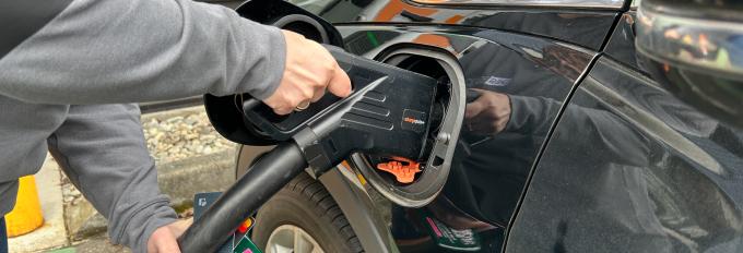 A driver plugs in an electric vehicle to a charging station