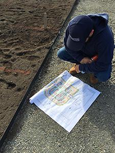 A Buildings & Grounds employee studies the planting plan before marking the ground with spraypaint.