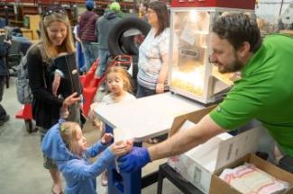 A child gets a bag of popcorn handed to her at the Surplus Grand Re-opening event.
