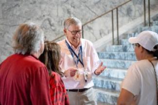 Volunteer Bob Schafer talks to a small tour group near steps inside the Capitol Rotunda.