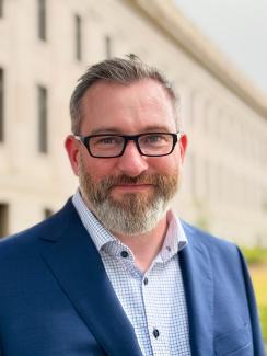 Matt Jones in a blue suite jacket and wearing glasses.