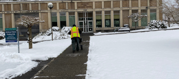 A DES employee spreads ice melt on the sidewalk in front of the State Archives Building.