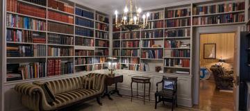 A picture of the library in the Governor's mansion that shows shelves lined with books and a chandelier hanging from the ceiling