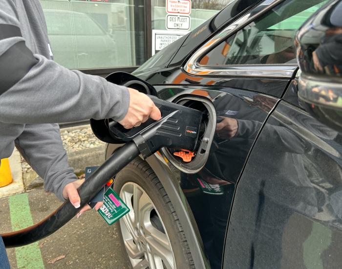 A driver plugs in an electric vehicle to a charging station