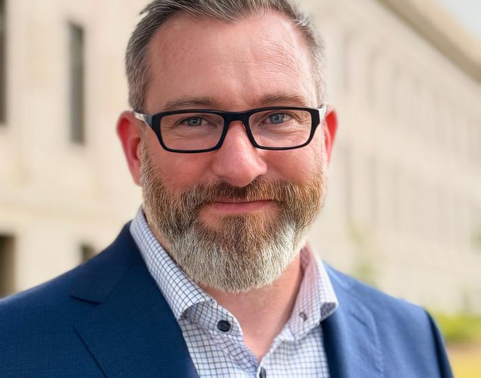 Matt Jones in a blue suite jacket and wearing glasses.