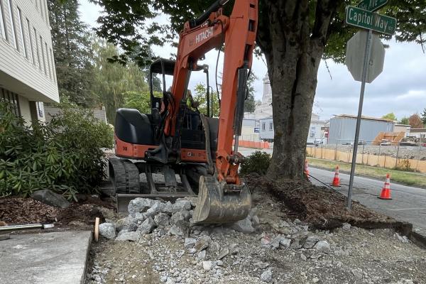 A bucket loader rips up sidewalk during construction