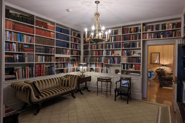 A picture of the library in the Governor's mansion that shows shelves lined with books and a chandelier hanging from the ceiling