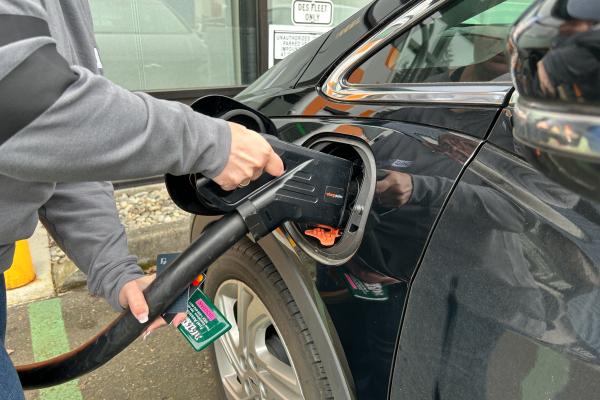 A driver plugs in an electric vehicle to a charging station
